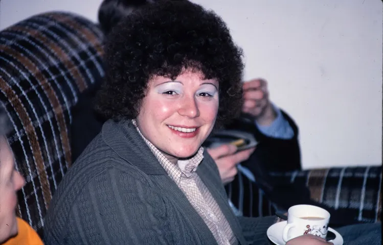 Restored slide of a smiling woman with curly hair holding a cup of tea